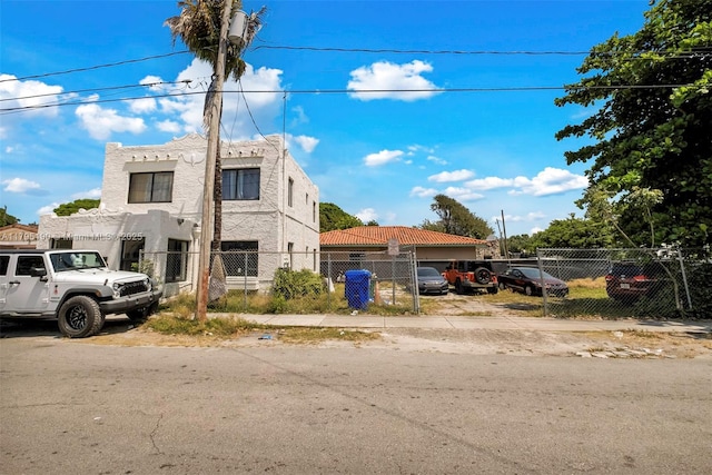 view of front of house with stucco siding, fence private yard, and uncovered parking