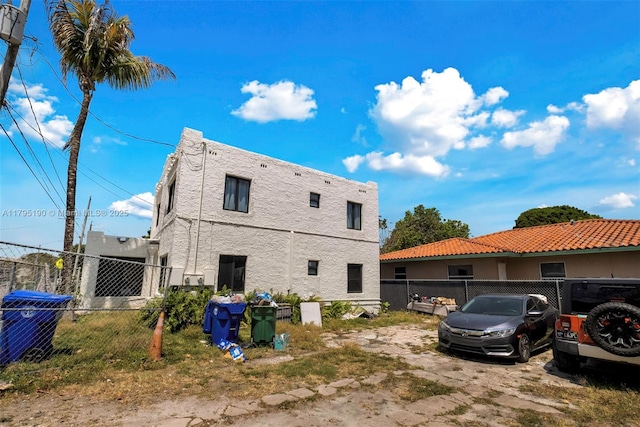 rear view of property featuring central AC unit, stucco siding, and fence