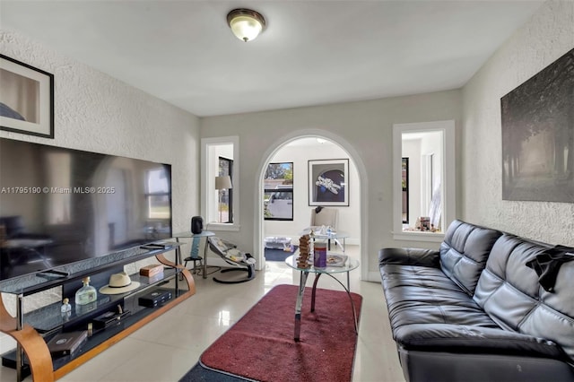 living area with tile patterned flooring and a textured wall