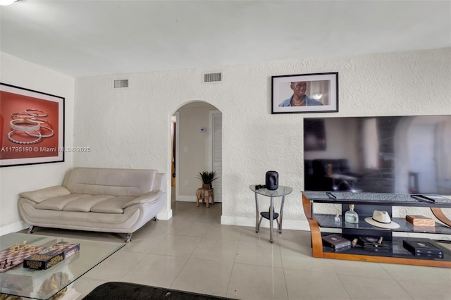 living room featuring visible vents, arched walkways, a textured wall, and baseboards