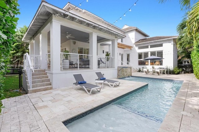 rear view of property with a ceiling fan, stucco siding, a patio area, and an outdoor pool