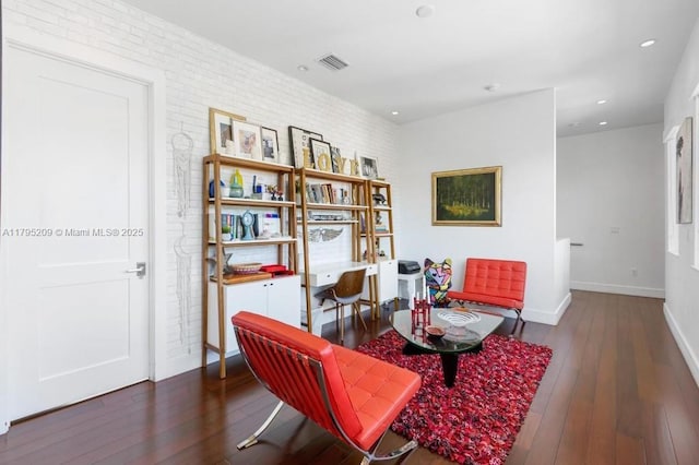 living area with wood-type flooring, visible vents, brick wall, baseboards, and recessed lighting