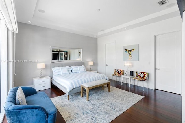 bedroom with a raised ceiling, dark wood-type flooring, recessed lighting, and visible vents