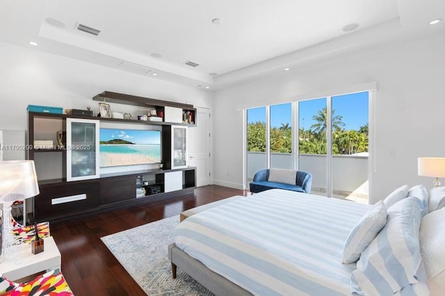 bedroom with recessed lighting, a tray ceiling, visible vents, and wood finished floors