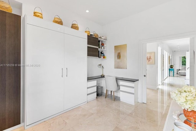interior space with recessed lighting, open shelves, marble finish floor, and built in desk