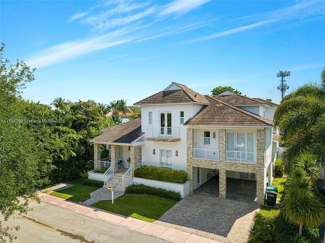 view of front of house featuring a tiled roof, driveway, a carport, stone siding, and stucco siding
