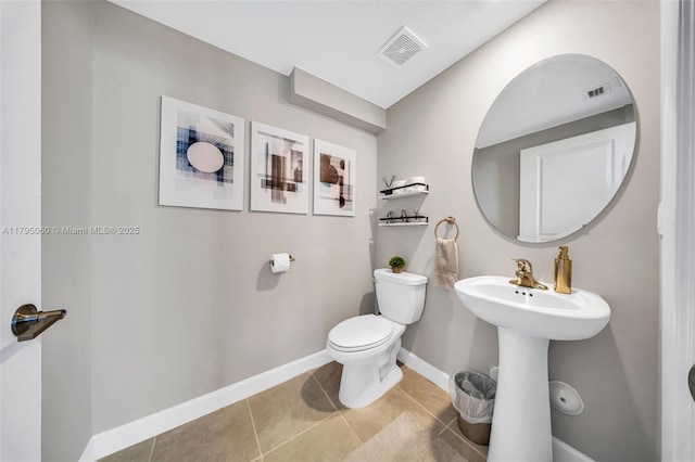 half bathroom featuring toilet, tile patterned floors, visible vents, and baseboards