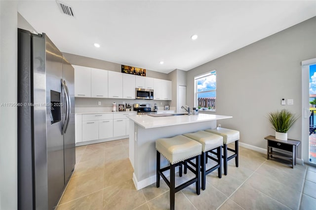 kitchen featuring light countertops, stainless steel appliances, a breakfast bar, and light tile patterned floors