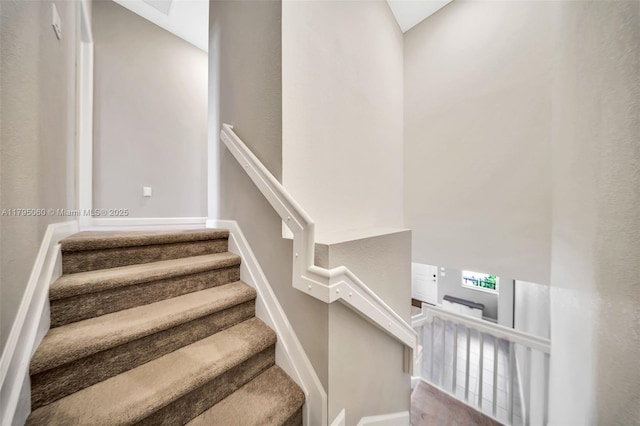 stairs featuring baseboards and a high ceiling