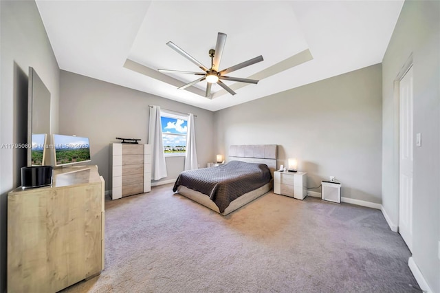 carpeted bedroom with baseboards, ceiling fan, and a raised ceiling