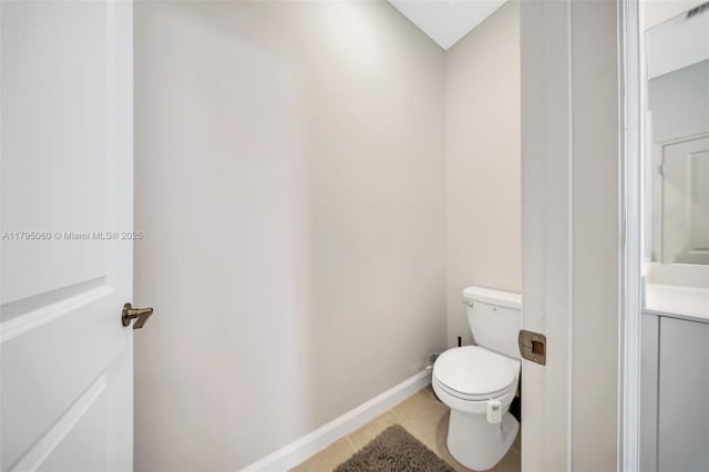 bathroom featuring tile patterned flooring, vanity, toilet, baseboards, and a skylight