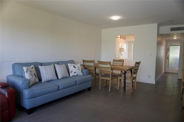 living room with visible vents, dark tile patterned floors, and baseboards