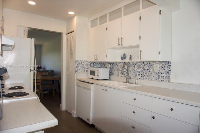 kitchen featuring white appliances, white cabinetry, a sink, and light countertops