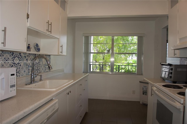 kitchen with a sink, light countertops, white appliances, white cabinetry, and dark tile patterned flooring
