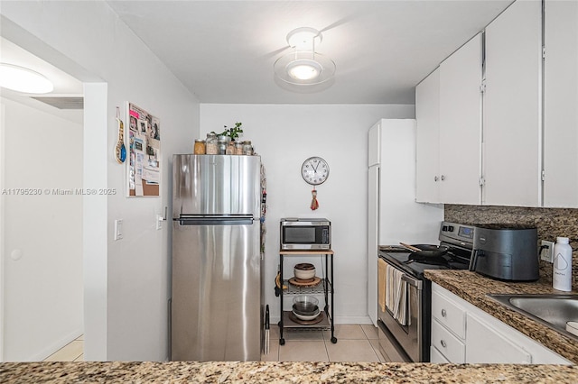 kitchen featuring white cabinets, light tile patterned flooring, baseboards, and appliances with stainless steel finishes