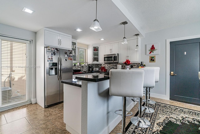 901 NW 22nd Pl, Miami, FL 33125 - kitchen featuring backsplash, a kitchen bar, dark countertops, appliances with stainless steel finishes, and glass insert cabinets