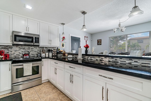901 NW 22nd Pl, Miami, FL 33125 - kitchen featuring backsplash, pendant lighting, dark countertops, appliances with stainless steel finishes, and white cabinetry