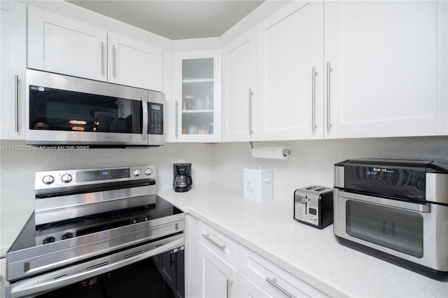 kitchen with light countertops, glass insert cabinets, white cabinetry, and stainless steel appliances