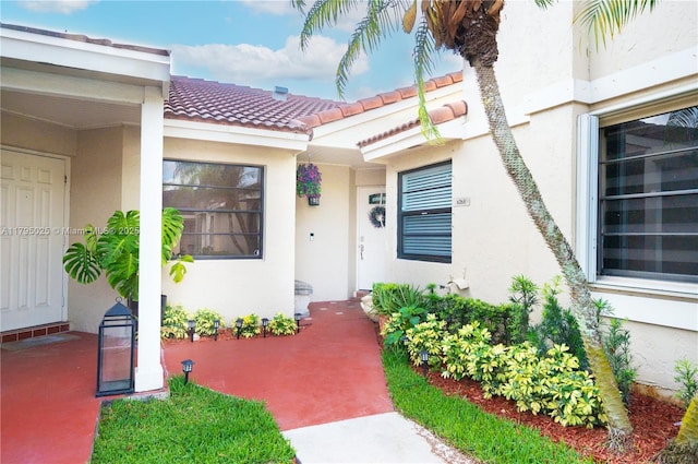 view of exterior entry featuring stucco siding and a tiled roof