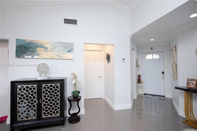 tiled foyer entrance featuring baseboards, ornamental molding, and visible vents