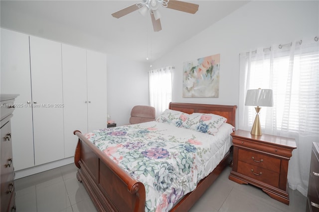 bedroom with a ceiling fan, light tile patterned floors, lofted ceiling, and a closet