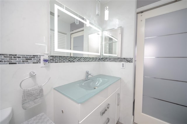bathroom featuring vanity, toilet, and tile walls