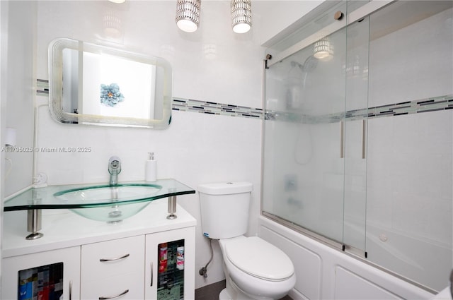 full bath with vanity, combined bath / shower with glass door, and toilet