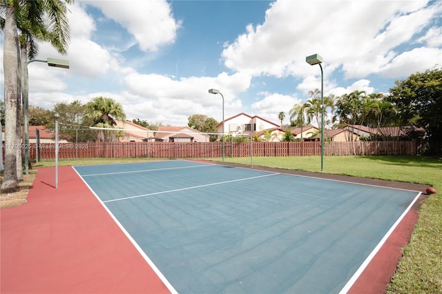 view of basketball court with a yard and fence