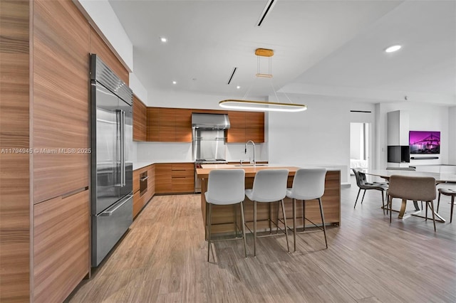 kitchen with stainless steel built in fridge, light countertops, modern cabinets, and brown cabinets