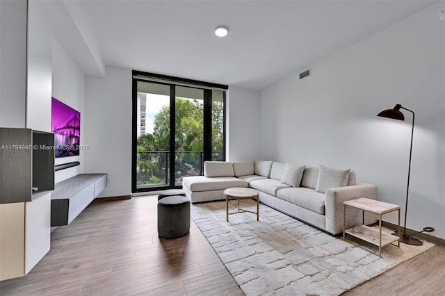 living room featuring visible vents, baseboards, and wood finished floors