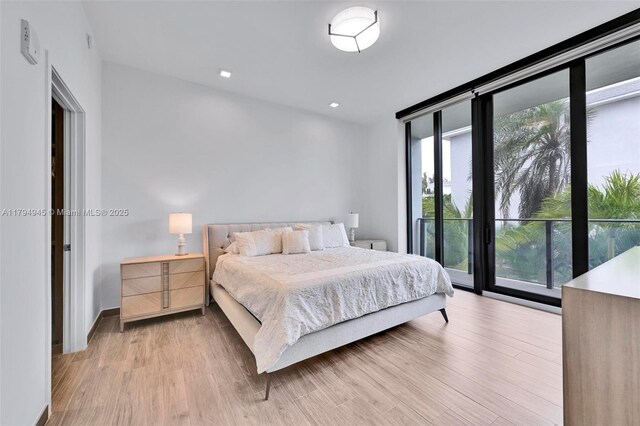 bedroom with recessed lighting, light wood-style flooring, floor to ceiling windows, and multiple windows