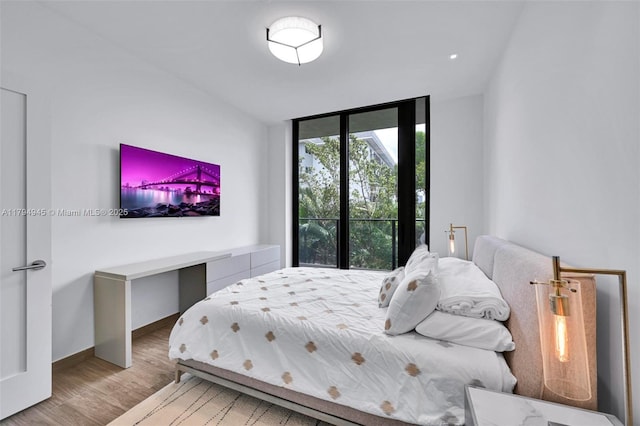bedroom with baseboards, a wall of windows, and wood finished floors