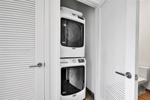 laundry area featuring laundry area, wood finished floors, and stacked washer and clothes dryer