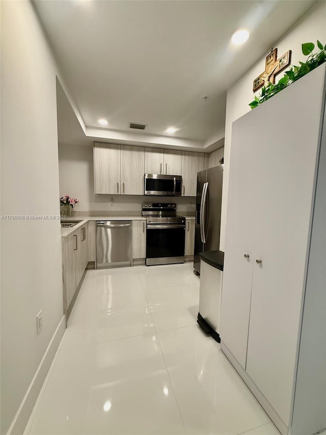 kitchen with modern cabinets, light countertops, light brown cabinets, stainless steel appliances, and recessed lighting