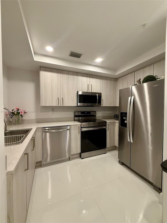 kitchen with a sink, light brown cabinets, stainless steel appliances, visible vents, and modern cabinets