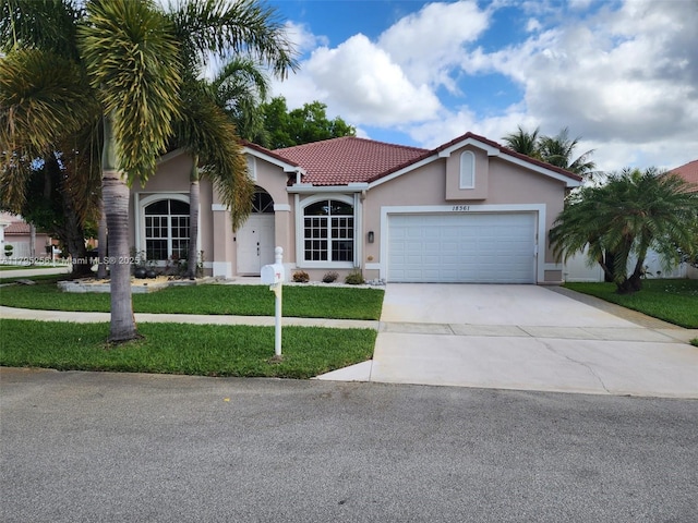 view of front of house featuring an attached garage, driveway, a tile roof, stucco siding, and a front yard