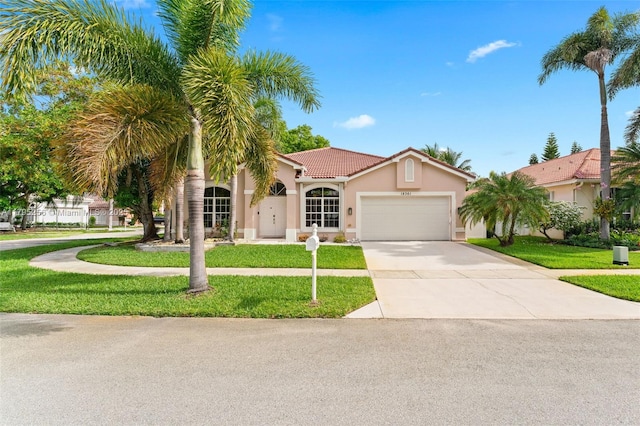 mediterranean / spanish-style house with an attached garage, stucco siding, a tile roof, concrete driveway, and a front lawn