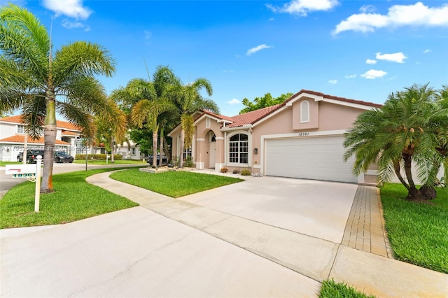 mediterranean / spanish house with an attached garage, stucco siding, a tile roof, a front yard, and driveway