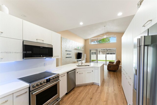 kitchen with a peninsula, lofted ceiling, open floor plan, a ceiling fan, and appliances with stainless steel finishes