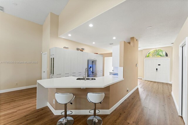 kitchen featuring baseboards, light wood-style flooring, high end fridge, and a sink