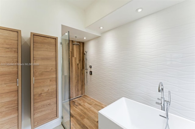 full bath featuring walk in shower, wood finished floors, a freestanding tub, and a sink