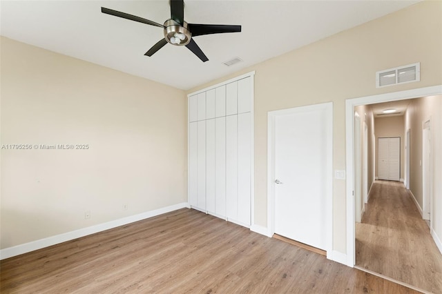 unfurnished bedroom featuring baseboards, a closet, light wood finished floors, and visible vents