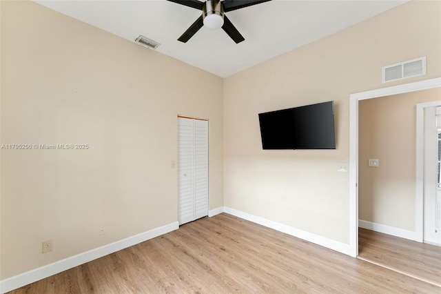 unfurnished bedroom featuring baseboards, light wood-type flooring, visible vents, and a closet