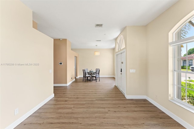 corridor featuring light wood-type flooring, baseboards, and visible vents