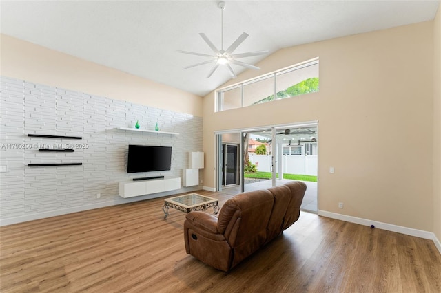 living room with baseboards, high vaulted ceiling, ceiling fan, and wood finished floors