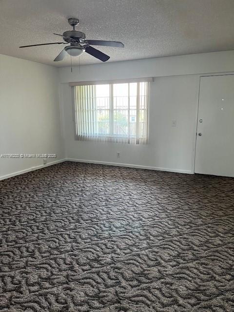 carpeted spare room featuring baseboards, a ceiling fan, and a textured ceiling