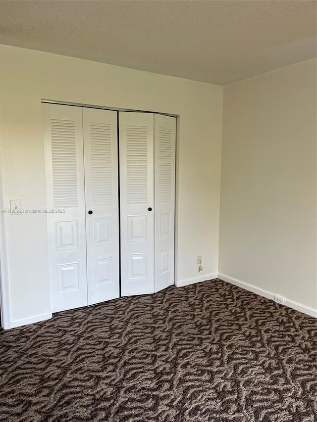unfurnished bedroom with carpet floors, baseboards, and a closet