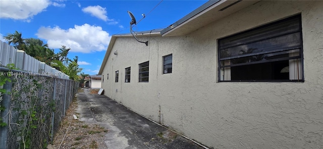 view of side of property featuring stucco siding and fence