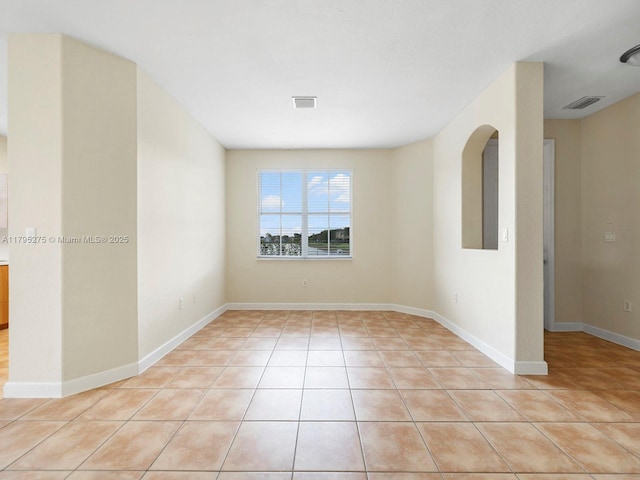 empty room featuring light tile patterned floors, baseboards, and visible vents