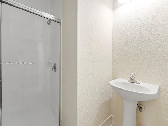 bathroom featuring a textured wall and a stall shower